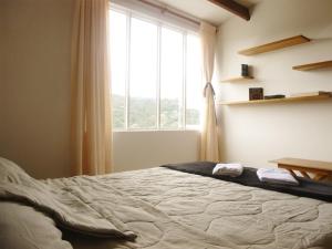 a bedroom with a bed and a large window at Hostal Café Casa Caturro in Manizales