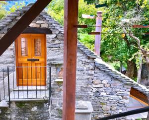 ein Steinhaus mit einer orangefarbenen Tür und einer Stange in der Unterkunft Rustici Maggia in Aurigeno