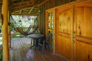 een veranda met een tafel en stoelen en een hangmat bij Hotel y Resort Quinta del Sol in San José Pinula