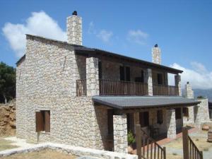 - un bâtiment en pierre avec un balcon au-dessus dans l'établissement Samaria Village, à Omalós