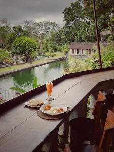 a table with eggs and a drink on a balcony at Tirta Ayu Hotel and Restaurant in Tirtagangga