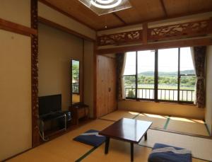 ein Wohnzimmer mit einem Tisch und einem großen Fenster in der Unterkunft Suimeiso in Yamanakako
