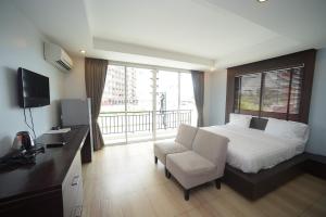 ein Schlafzimmer mit einem Bett, einem Stuhl und einem Fenster in der Unterkunft Villa Navin Beach Residence in Jomtien Beach