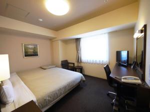 a hotel room with a bed and a desk and a window at Hotel Route-Inn Sapporo Chuo in Sapporo