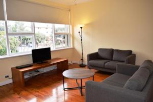 Glenelg Holiday Apartments-Ellis في أديلايد: غرفة معيشة مع أريكة وطاولة