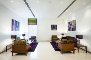 a lobby with tables and chairs and paintings on the wall at Holiday Bahrain Hotel in Manama