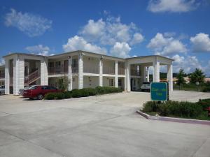 un gran edificio con un estacionamiento delante de él en Carom Inn a Travelodge by Wyndham Denham Springs-Baton Rouge en Denham Springs