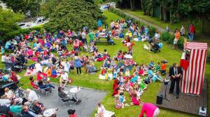 Une foule de gens assis dans l'herbe en train de regarder un discours dans l'établissement Round Tower Hotel, à Ardmore