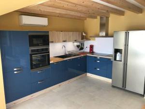 a kitchen with blue cabinets and a stainless steel refrigerator at Appartement en bord de Mer in Saintes-Maries-de-la-Mer