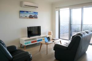 Penneshaw Oceanview Apartments في بنيشو: غرفة معيشة مع أريكة وتلفزيون