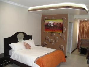 um quarto com uma cama e um quadro na parede em Kismet Hotel em Pietermaritzburg