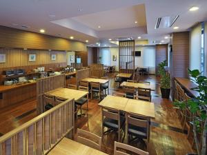 a restaurant with wooden tables and chairs and a bar at Hotel Route Inn Hitachinaka in Hitachinaka