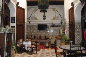 a dining room with tables and chairs and a tv at Maison Famille Tazi in Fez
