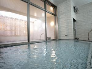 einen Pool mit Wasser in einem Zimmer mit Fenstern in der Unterkunft Hotel La'gent Plaza Hakodate Hokuto in Hokuto