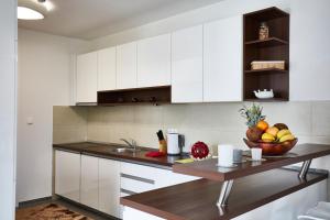 una cocina con armarios blancos y un bol de fruta en Apartments Panamera en Sarajevo