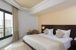 a bedroom with a large bed and a large window at Le Corail Suites Hotel in Tunis