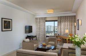 فندق أجنحة لو كوراي في تونس: غرفة معيشة مع أريكة وغرفة طعام