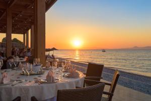 a table with wine glasses and the ocean at sunset at Avra Beach Resort in Ixia