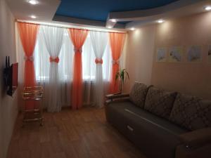 ein Wohnzimmer mit Sofa und orangefarbenen Vorhängen in der Unterkunft Leninskiy Prospekt 25 in Norilsk