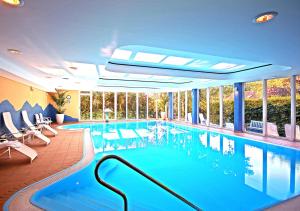 a large swimming pool with chairs and a swimming pool at Ringhotel Warnemünder Hof in Warnemünde