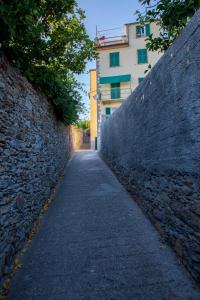 an alley with a building behind a stone wall at Madüneta 5 Terre in Corniglia