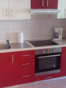 een keuken met rode kasten en een fornuis met oven bij Apartment Marta in Nin