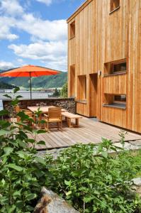 eine Holzterrasse mit einem Tisch und einem Sonnenschirm in der Unterkunft Smart Wood House in Tamsweg