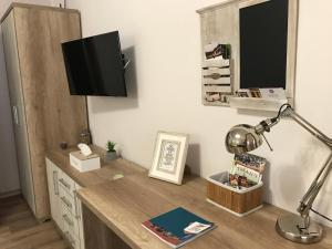 a desk with a lamp and a tv on a wall at Origo Vendégház in Sárospatak