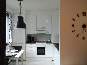 una cocina con armarios blancos y un reloj en la pared en A lovely one-room apartment near the city centre., en Vaasa