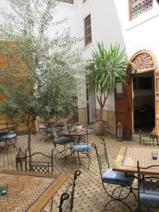 eine Terrasse mit Tischen, Stühlen und Bäumen in der Unterkunft Riad Attarine in Fès