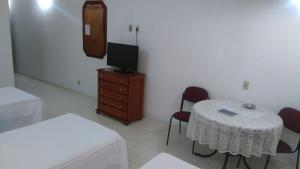 a room with a table and a tv on a dresser at Obeid Plaza Hotel in Bauru