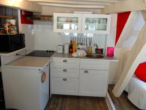 a small white kitchen with a sink and a bed at Chez Titi in Bayeux