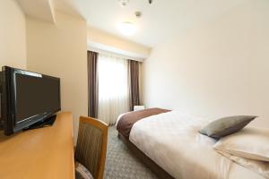 um quarto de hotel com uma cama e uma televisão de ecrã plano em Osaka Tokyu REI Hotel em Osaka