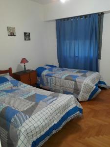 2 camas en una habitación con cortinas azules en Apartamento Lautaro en Buenos Aires