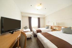 Habitación de hotel con 2 camas y TV de pantalla plana. en Osaka Tokyu REI Hotel en Osaka