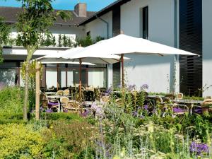 a patio with tables and chairs and an umbrella at Landhaus Beckmann in Kalkar