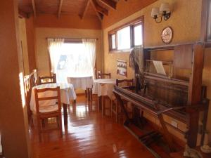 uma sala de jantar com duas mesas e um piano em Hosteria Rukahué em El Calafate