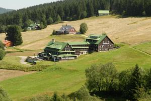 un groupe de maisons sur une colline herbeuse dans l'établissement Horský hotel Žižkova bouda, à Pec pod Sněžkou