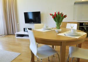 a wooden table with a vase of red flowers on it at IRS ROYAL APARTMENTS Apartamenty IRS Fregata in Gdańsk