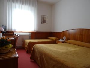 a hotel room with two beds and a window at Hotel Roma in Cividale del Friuli