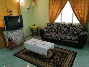 a living room with a couch and a tv at Chalet Desa Halban in Kangar