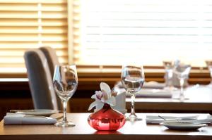 a table with wine glasses and a flower in a vase at Maitlandfield House Hotel in Haddington