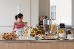 a woman standing in a kitchen with a counter full of food at Hotel Mediterraneo in Sottomarina