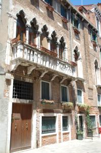 ヴェネツィアにあるResidenza Ofeliaの木製のドアとバルコニーが備わる古いレンガ造りの建物