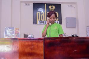 a woman standing behind a desk talking on a cell phone at The Palace Guest House in Harare