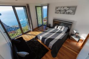 ein Schlafzimmer mit einem Bett in einem Zimmer mit großen Fenstern in der Unterkunft Villa Maciel in Calheta