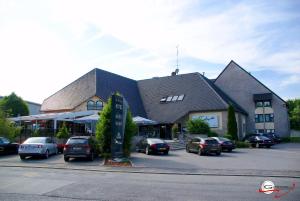 ein großes Gebäude mit Autos auf einem Parkplatz in der Unterkunft Threeland Hotel in Petingen