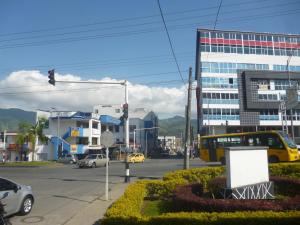 a city street with a yellow bus and a building at Hotel Guadalupe Plaza in Pereira