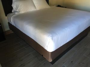 a bed with white sheets and a wooden floor at Colton Inn in Colton