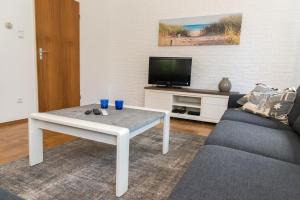 ein Wohnzimmer mit einem weißen Couchtisch und einem TV in der Unterkunft Hello Zeeland - Vakantiehuis Het Heem 39 in Breskens